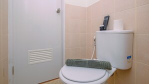 Une petite salle de bain privée comprenant des toilettes, une serviette et un porte-rouleau de papier toilette.