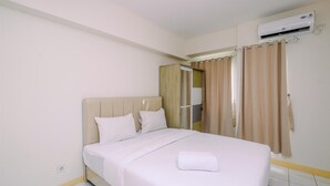 A hotel room with a bed, a wardrobe, an air conditioning unit, and a bathroom door. - Nice and Comfort Studio at 25th Floor Podomoro Golf View Apartment (Gunung Putri)