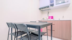 Una pequeña cocina con una mesa, sillas, un lavabo y armarios.