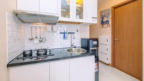 A modern kitchen with white cabinets, a black countertop, a stainless steel sink, and a built-in stove. There is a coffee maker and a dish rack visible.