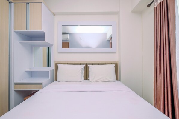 A neatly arranged bedroom with a bed, a bedside table, a mirror, and a wardrobe.