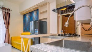 A modern kitchen with a granite countertop, stainless steel appliances, and a built-in gas stove. - Simply Design 2BR at Podomoro Golf View Apartment (Gunung Putri)