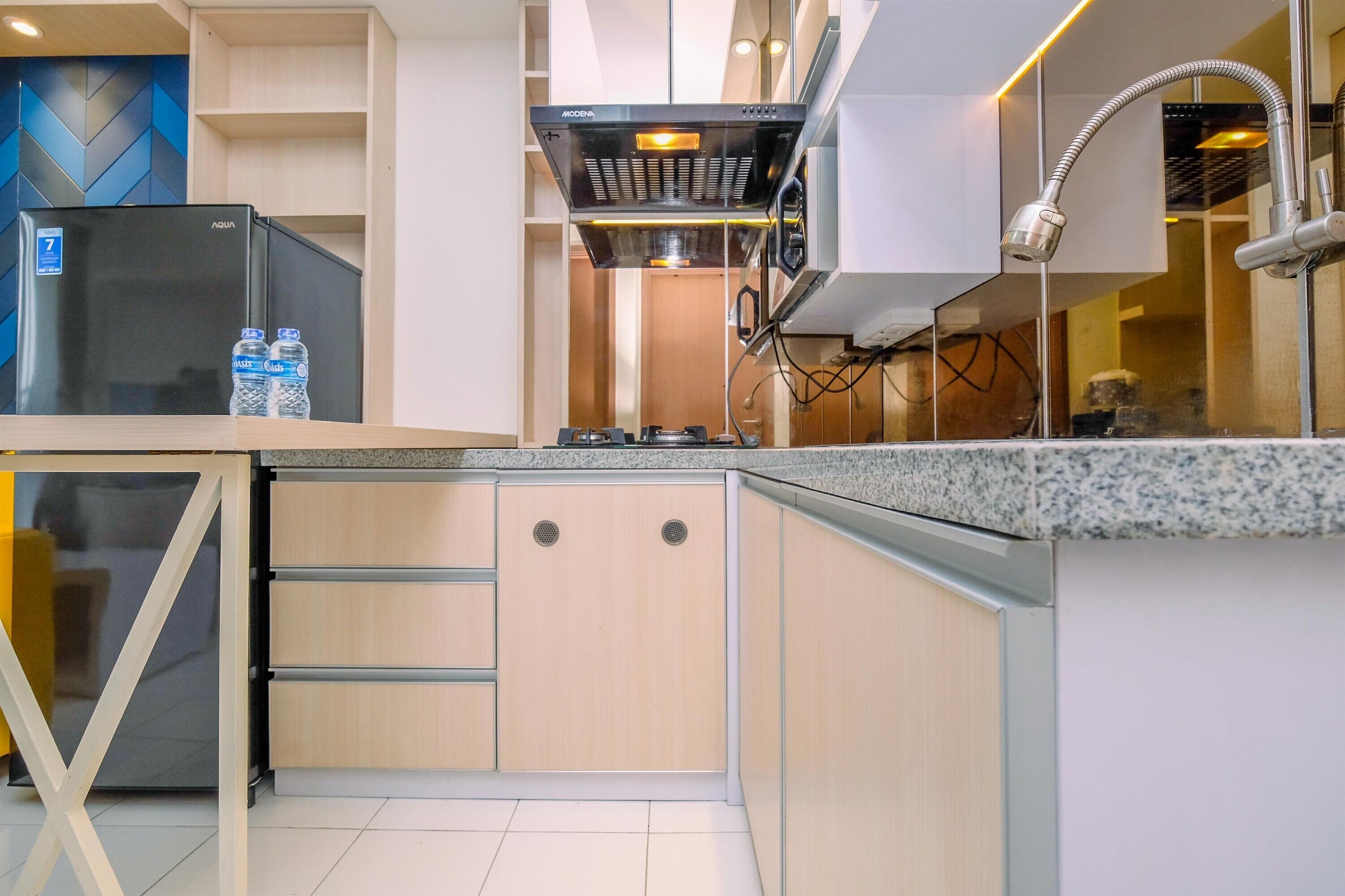 A modern kitchen with a black refrigerator, a water dispenser, and a stainless steel range hood.