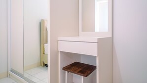 A bathroom with a white vanity, a mirror, and a wooden shelf. - Nice and Comfort 2BR at Podomoro Golf View Apartment (Gunung Putri)