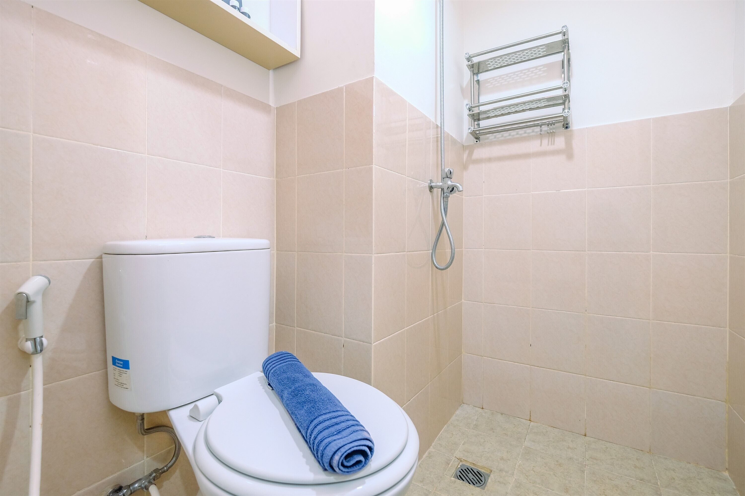 A bathroom with a white toilet, a blue towel, and a shower area.