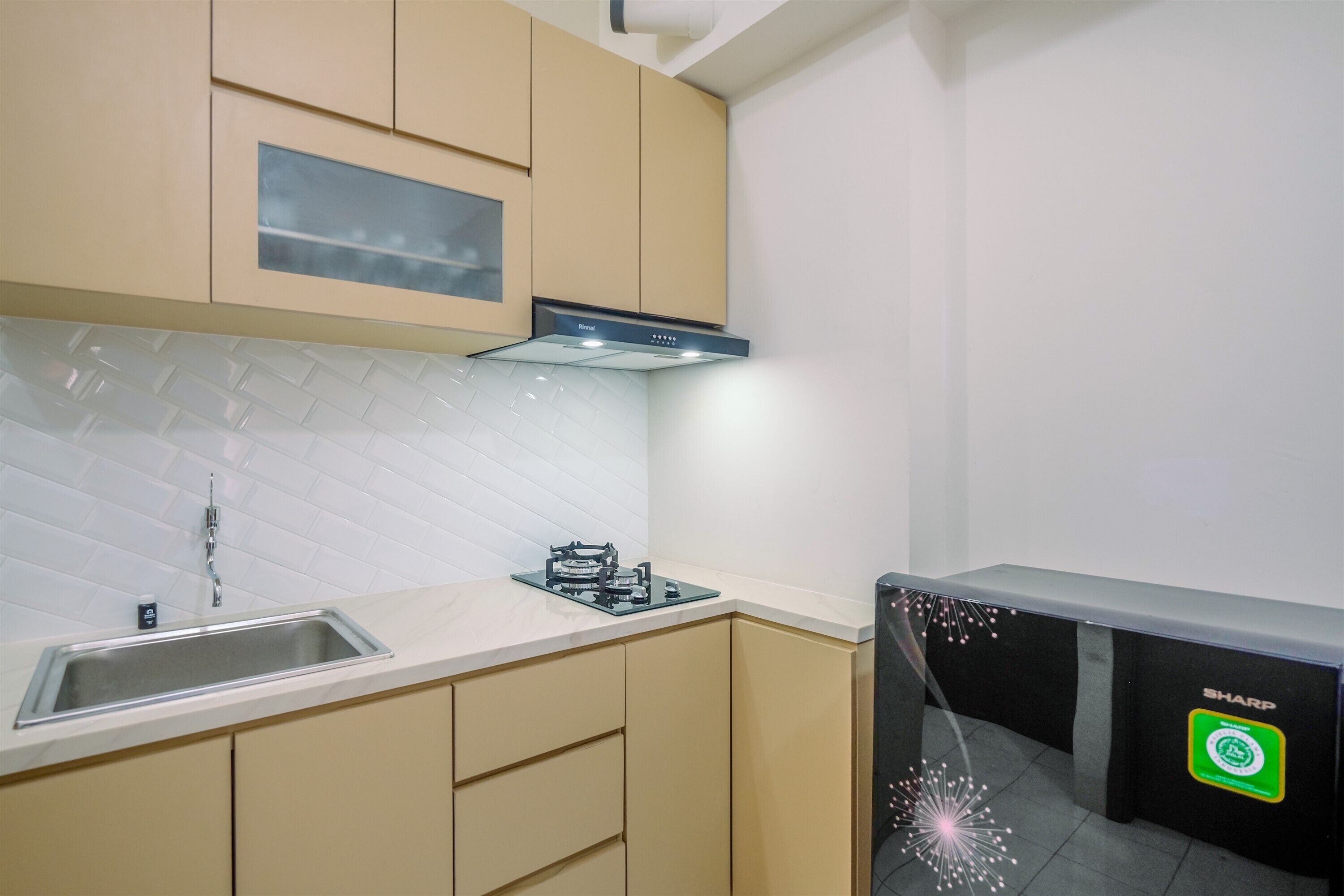 Une cuisine moderne avec des meubles de couleur beige, un évier en acier inoxydable et une cuisinière à gaz.