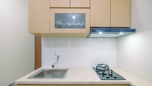 A modern kitchen with a built-in sink, a stove, and a range hood. - Nice and Comfort 2BR at Podomoro Golf View Apartment (Gunung Putri)