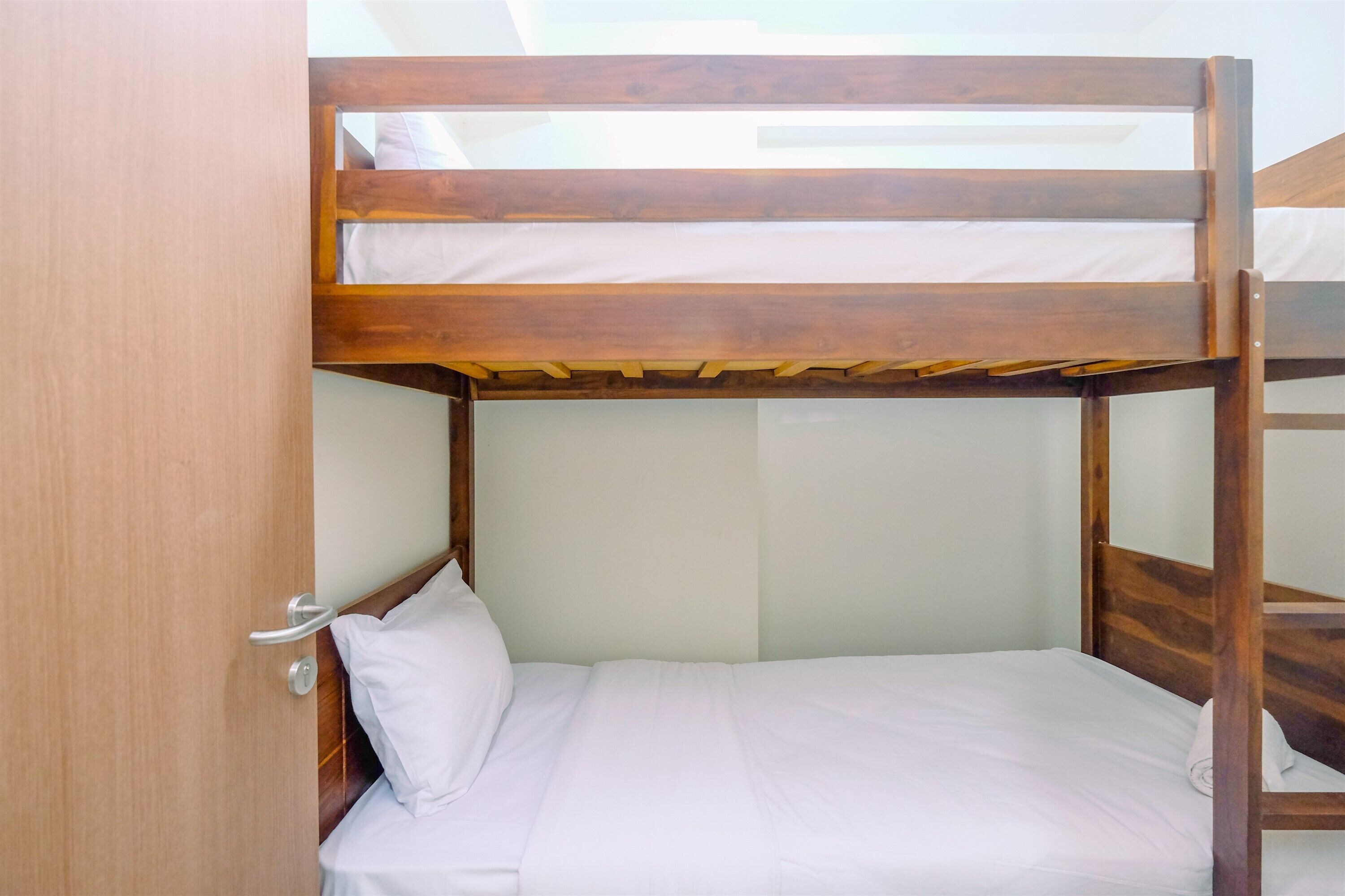 A bunk bed with a wooden frame and white bedding.