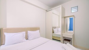 A hotel room with a bed, a bedside table, a mirror, and a window with curtains. - Nice and Comfort 2BR at Podomoro Golf View Apartment (Gunung Putri)