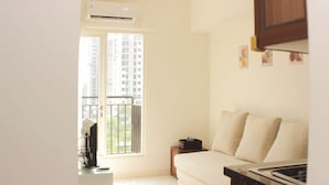 A modern kitchen with a built-in oven and a dining area with a white table and chairs. - Nice and Comfort 1BR with Extra Room at Podomoro Golf View Apartment (Gunung Putri)