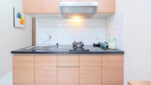 Une cuisine moderne avec des meubles en bois, un plan de travail noir, une cuisinière à gaz et un évier en acier inoxydable.