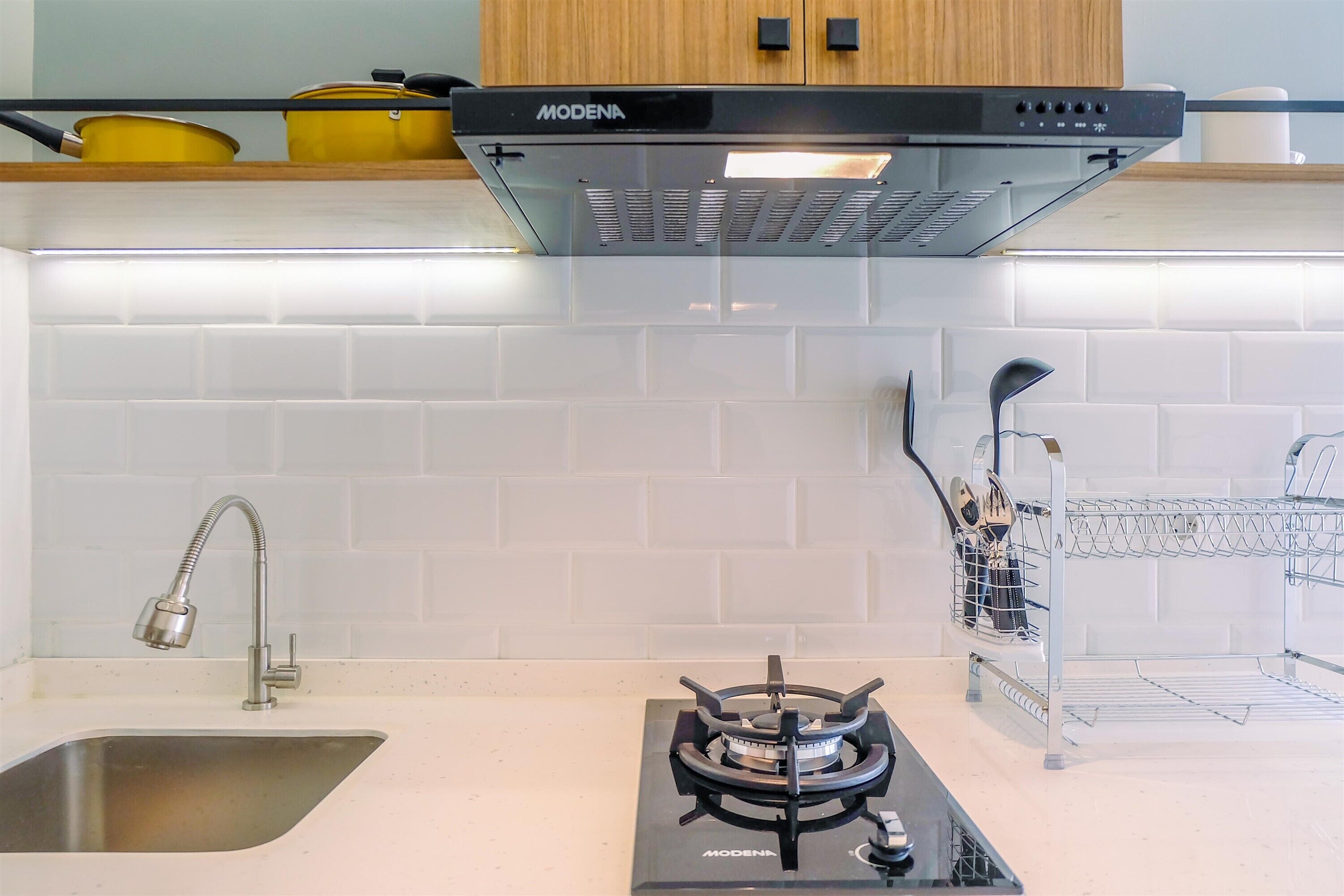Una cocina con estufa a gas, un lavamanos y una campana extractora.