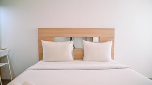 A neatly made bed with a wooden headboard and two white pillows. - Dashing Studio at Baileys Apartment (South Tangerang)
