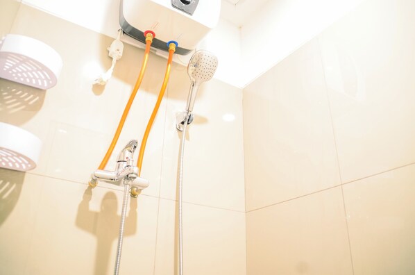A shower area with a handheld showerhead and a wall-mounted showerhead, both with hoses. - Dashing Studio at Baileys Apartment (South Tangerang)