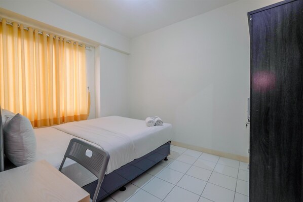 A small, clean room with a bed, a chair, a desk, and a wardrobe.