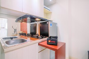 A modern kitchen with a gas stove, two sinks, and a travel bag on a wooden counter.
