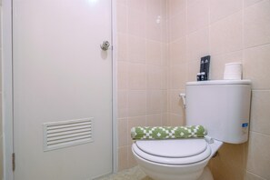 Un baño con inodoro, una toalla y un dispensador de papel higiénico.