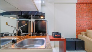 Une cuisine de taille réduite, équipée d’une cuisinière à gaz, d’un évier et d’un réfrigérateur compact.
