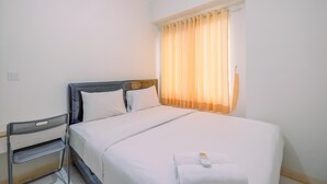 Une chambre d’hôtel avec un lit, une chaise et une fenêtre avec des rideaux.
