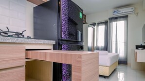 Une chambre d’hôtel moderne équipée d’une kitchenette, d’un lit et d’une grande fenêtre avec des rideaux.