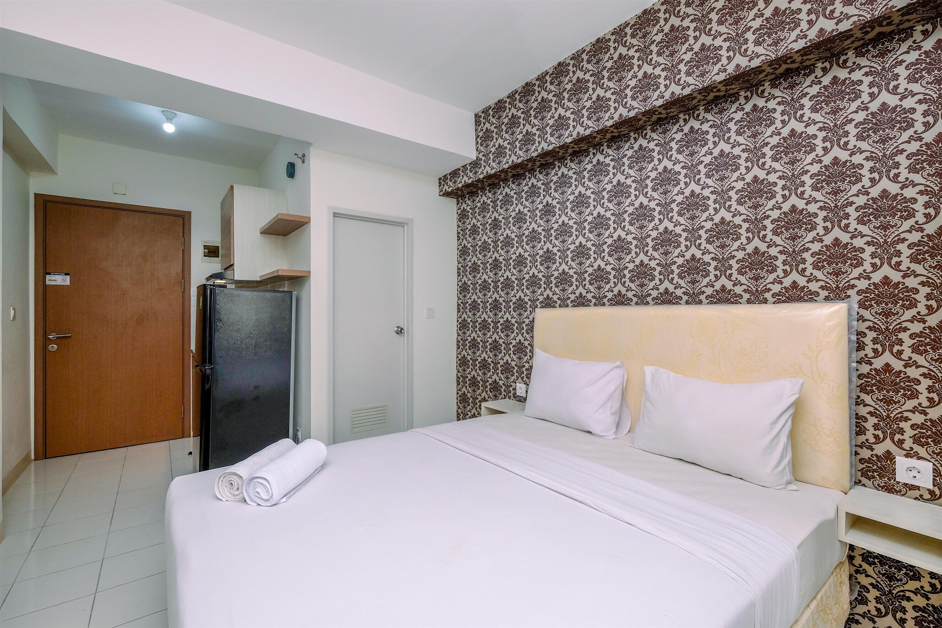 Una camera d'albergo con un letto, un armadio, uno specchio e una parete decorata.