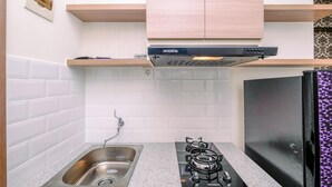 Une cuisine équipée d’un évier en acier inoxydable, d’une cuisinière à gaz et d’un réfrigérateur noir.