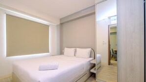 A modern bedroom with a large bed, a mirror, and a wooden floor. - Minimalist and Warm 2BR at 29th Floor Podomoro Golf View Apartment (Gunung Putri)