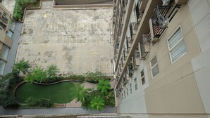 A rooftop pool area with a swimming pool, surrounded by greenery and adjacent to a residential building with balconies. - Comfort and Stylish 2BR at Podomoro Golf View Apartment (Gunung Putri)