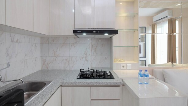 A modern kitchen with a gas stove, stainless steel sink, and marble backsplash. - Comfort and Stylish 2BR at Podomoro Golf View Apartment (Gunung Putri)