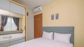A hotel room with a bed, a mirror, a wardrobe, and an air conditioning unit. - Best Deal and Tidy 2BR Podomoro Golf View Apartment (Gunung Putri)