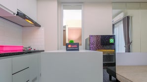 A modern kitchen with grey cabinets, a pink countertop, and a travel bag on the counter. - Best Deal and Tidy 2BR Podomoro Golf View Apartment (Gunung Putri)