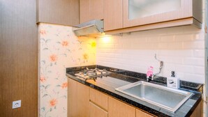Une cuisine avec des meubles en bois, un plan de travail noir, un évier en acier inoxydable et un papier peint à motifs floraux.