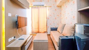 Un espace de vie compact comprenant un téléviseur à écran plat fixé au mur, un canapé, une table basse et un petit téléviseur posé sur un meuble.