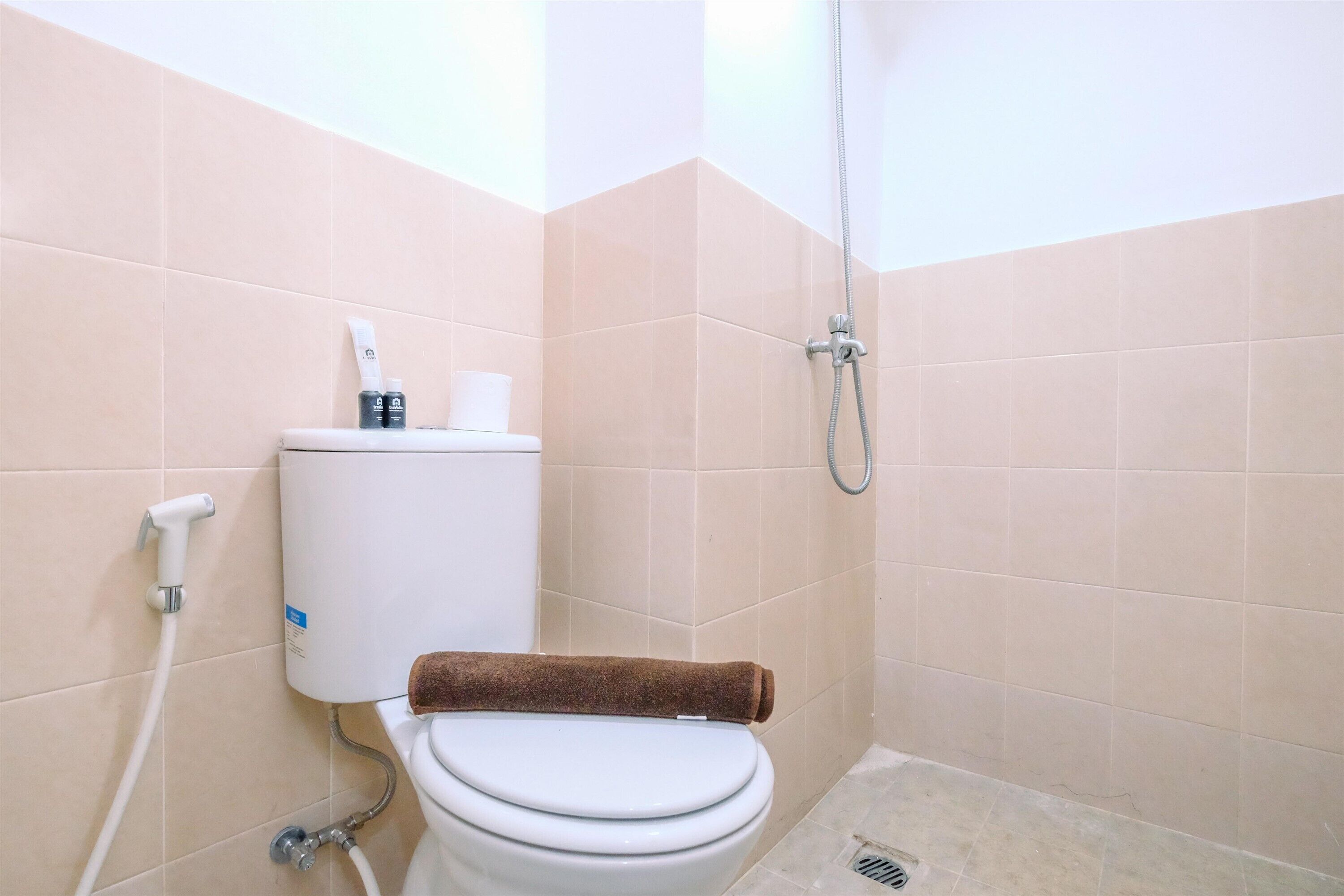 A bathroom with a toilet, a shower, and beige tiles.