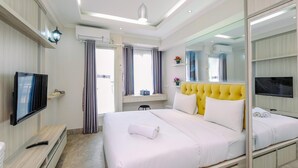 A modern hotel room with a large bed, a TV, a mirror, and a window with curtains. - Homey Studio Room at Podomoro Golf View Apartment (Gunung Putri)