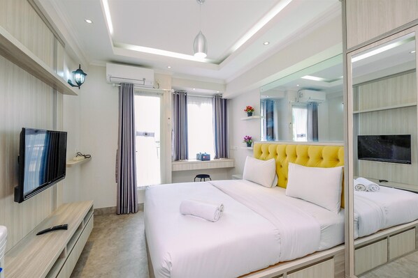 Une chambre d’hôtel moderne avec un grand lit, une télévision, un miroir et une fenêtre avec des rideaux.