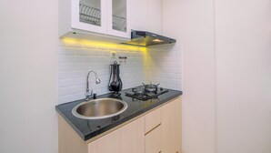 Una cocina compacta con un lavamanos de acero inoxidable, una estufa a gas y una campana extractora moderna.