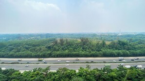 A highway with multiple lanes and vehicles, surrounded by dense green forest. - Comfy Stay 2BR at Podomoro Golf View Apartment (Gunung Putri)