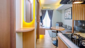A compact kitchenette with a stove, sink, and refrigerator. A small dining area with a table and chairs is visible. - Nice and Homey 2BR at Podomoro Golf View Apartment (Gunung Putri)