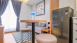 A compact living space with a kitchenette, a sofa, a dining table, and a refrigerator. - Nice and Homey 2BR at Podomoro Golf View Apartment (Gunung Putri)