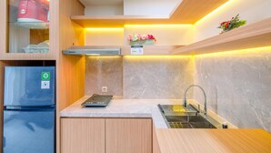 A modern kitchen with a built-in oven, a stainless steel sink, and wooden cabinets. - Tidy and Comfortable 2BR Podomoro Golf View Apartment (Gunung Putri)