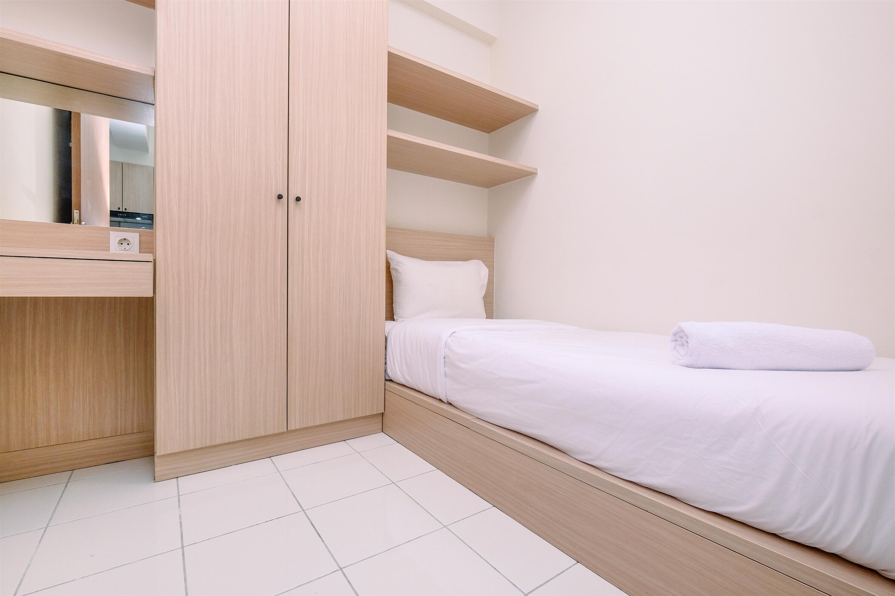 A bedroom with a bed, a wooden wardrobe, and a mirror.