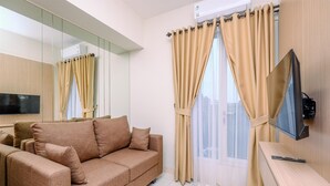 Un salon moderne avec un canapé, un téléviseur fixé au mur et des rideaux de couleur beige.