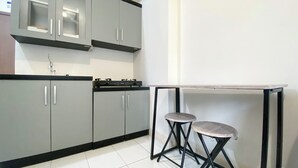 A modern kitchen with grey cabinets, a black countertop, and a small bar stool.