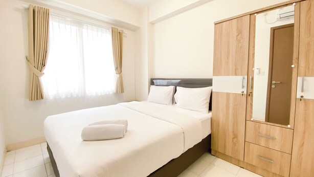 A hotel room with a bed, curtains, a wardrobe, and a window.
