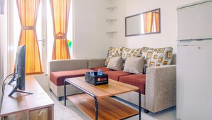 A modern living room with a sofa, a coffee table, a flat-screen TV, and a refrigerator.