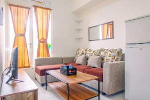 A modern living room with a sofa, a coffee table, a flat-screen TV, and a refrigerator.