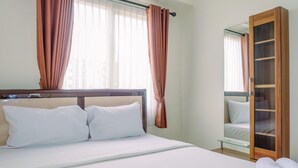A hotel room with a bed, curtains, a wooden wardrobe, and a window with blinds.