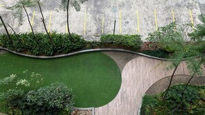 A landscaped area with a curved pathway, green artificial turf, and various plants. - Best Choice and Homey 2BR Podomoro Golf View Apartment (Gunung Putri)