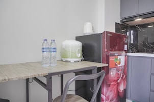 Et køkken med et træbord, to vandflasker, en hvid kaffemaskine, et rødt køleskab og en mikrobølgeovn.